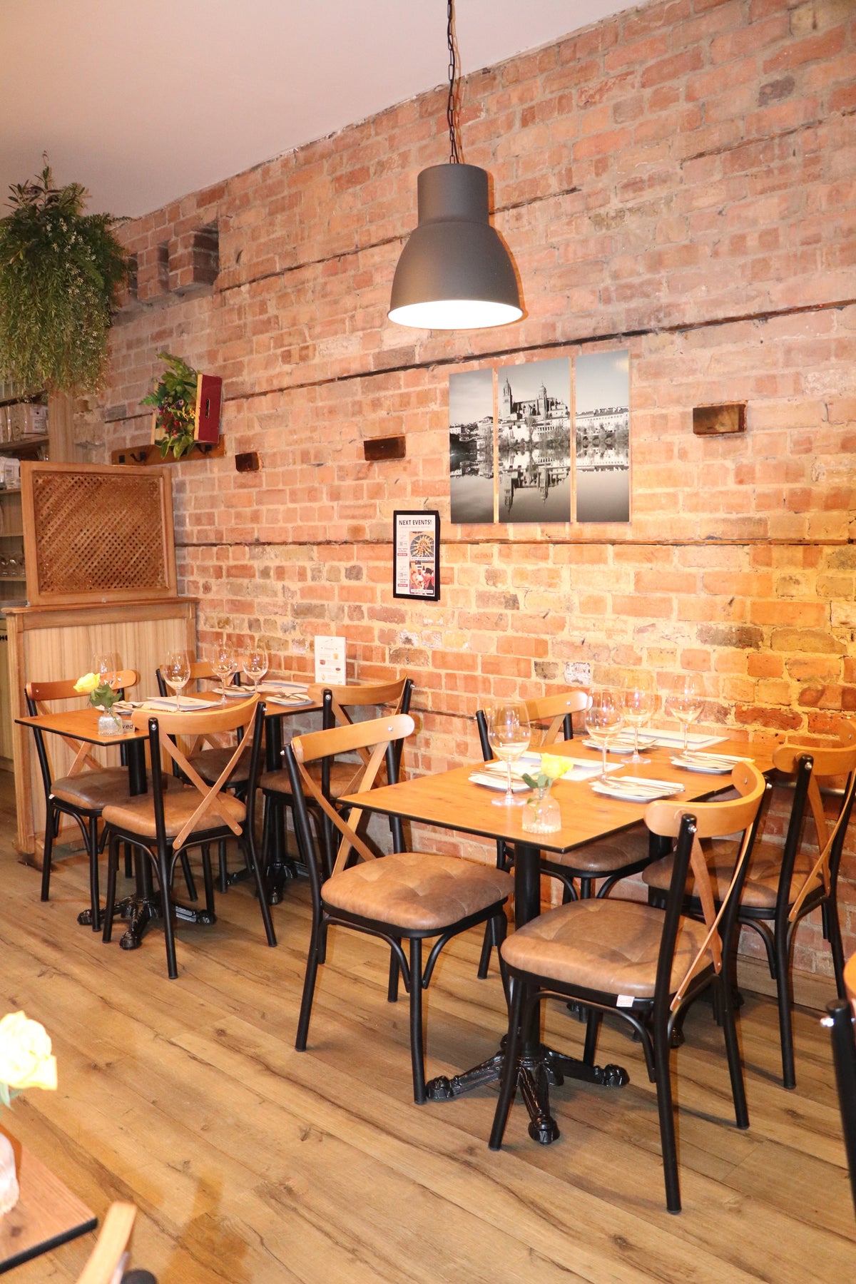 Tables set for guests inside Casa Manolo Clapham, with warm brick walls and pendant lighting