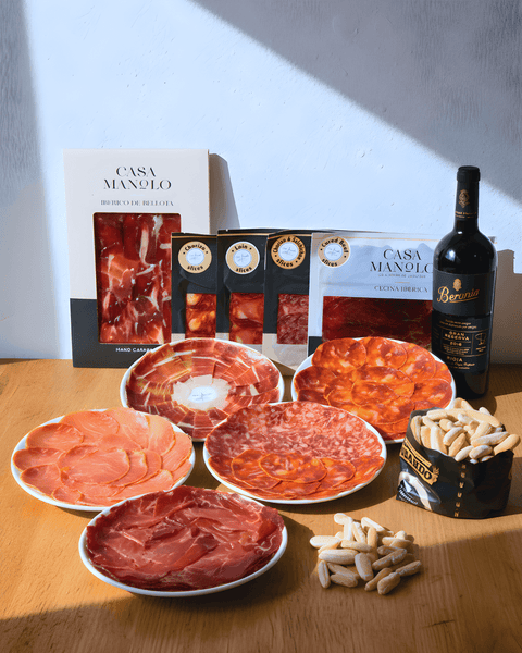 Iberico Bellota Rioja Set with assorted cured meats, Rioja Gran Reserva, and snacks on a wooden table.