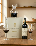 Matarromera wine box with decanter and two glasses of wine on a wooden table.