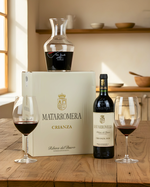 Matarromera wine box with decanter and two glasses of wine on a wooden table.